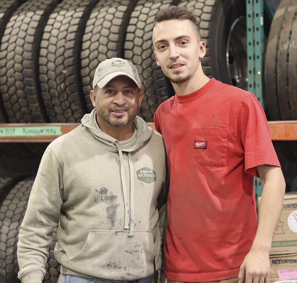 Deux hommes dans une usine devant un étagère de pneus