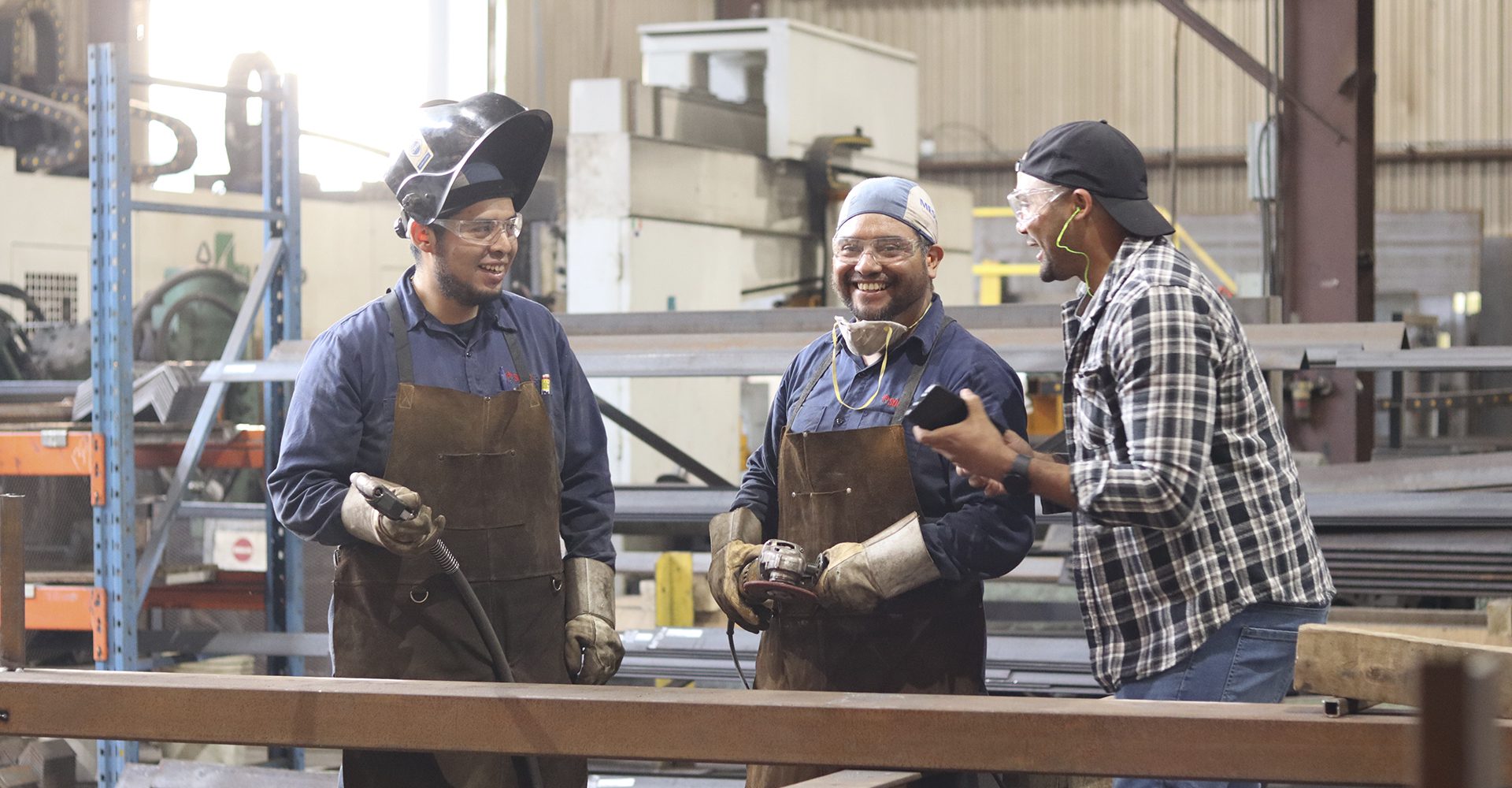 Trois hommes souriant dans une usine